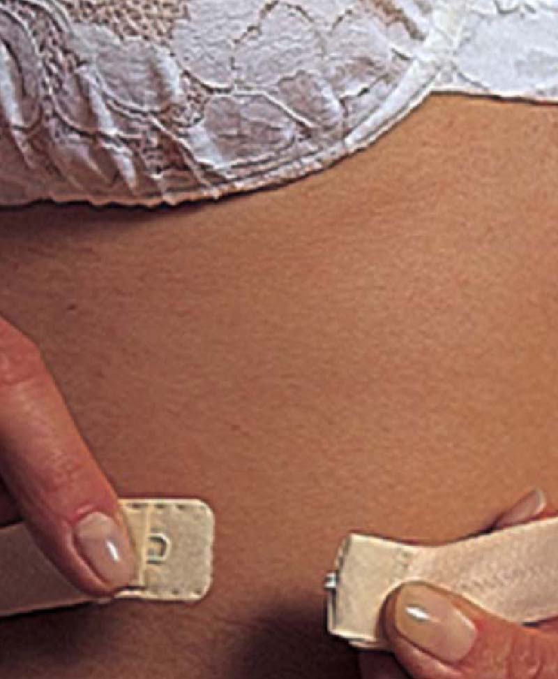 Image of wormen using the lowdown clip. She is joining the bottom clip below her bra. 